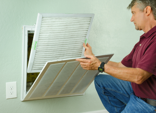 man installing airfilter into wall vent